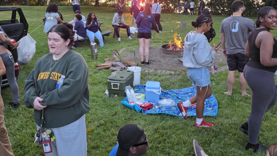 EOP students gather at a bonfire during the first week of their summer orientation program, as one of the famous Lake Ontario sunsets peeks through the trees.