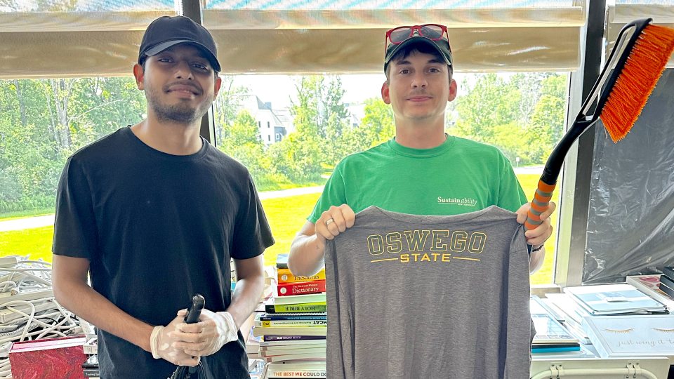 From left, Ananta Bhowmick Antik, a member of SUNY Oswego’s student sustainability team, and Maxon Ali, the university’s sustainability coordinator, show off some of the recycled items from the OzThrift effort. 