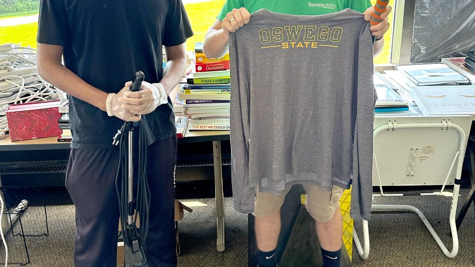 From left, Ananta Bhowmick Antik, a member of SUNY Oswego’s student sustainability team, and Maxon Ali, the university’s sustainability coordinator, show off some of the recycled items from the OzThrift effort. 