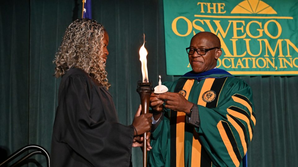 Student Association President Precious James lights the Torch of Learning with President Peter O. Nwosu during this year's Welcoming Torchlight Ceremony