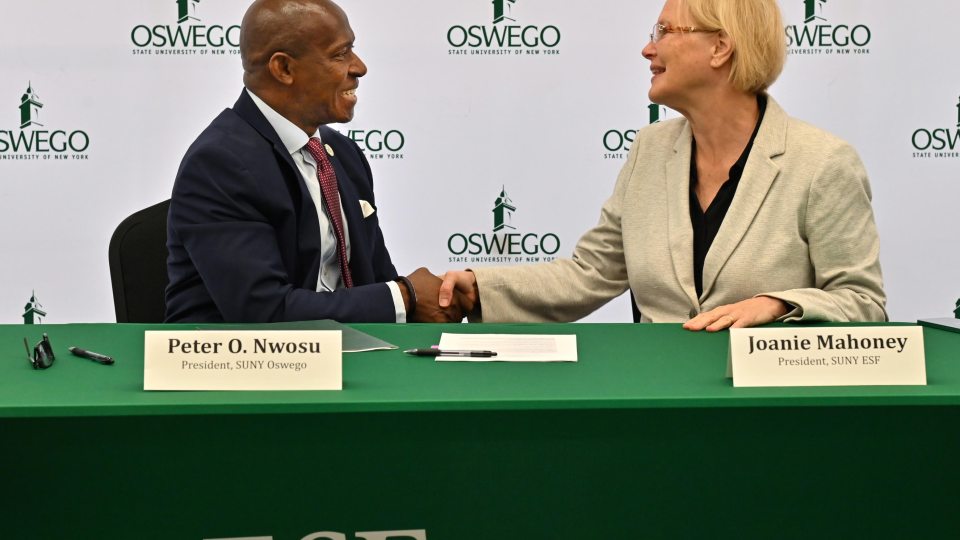 SUNY Oswego President Peter O. Nwosu shakes hands with SUNY ESF President Joanie Mahoney to finalize a shared services agreement between the institutions on Sept. 29. 