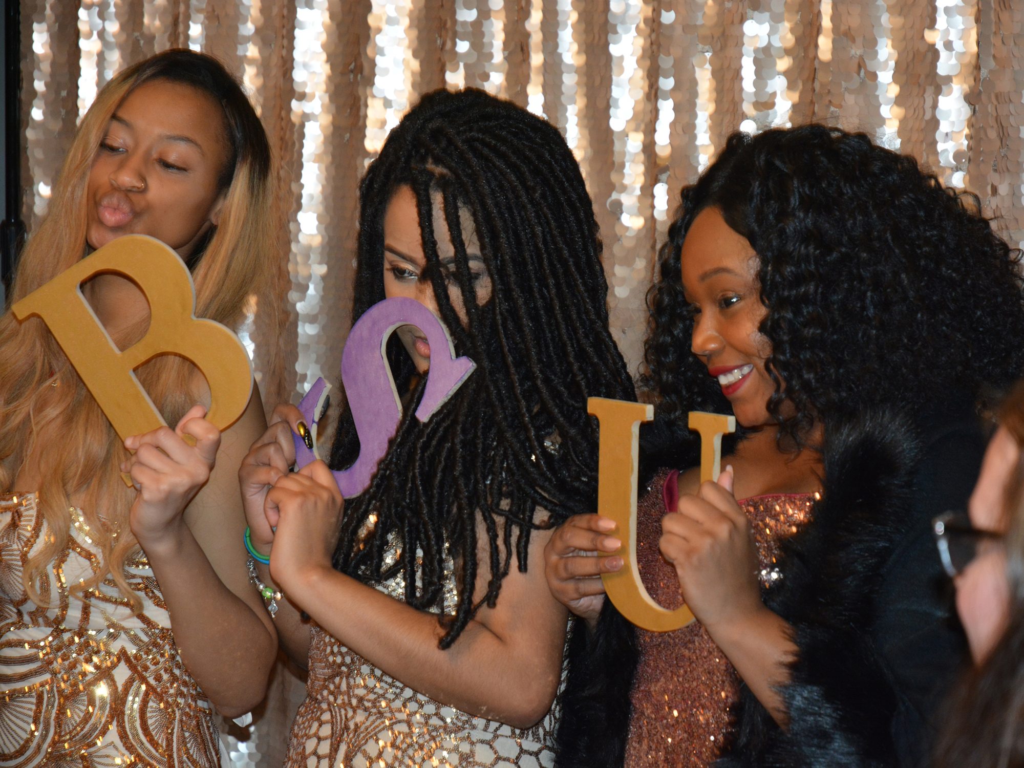 Students hold up letters B S U