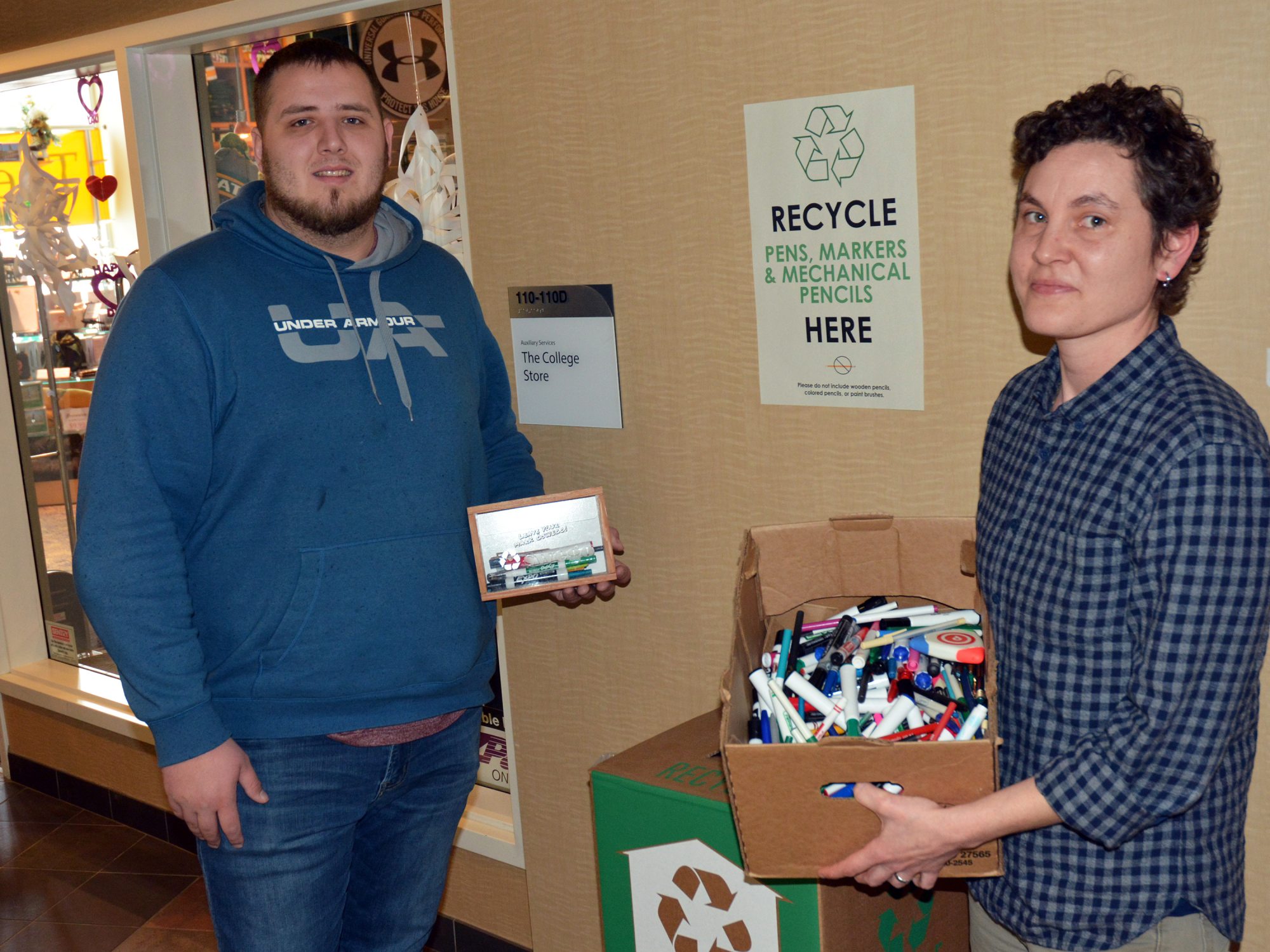 Kate Spector and student assistant Connor Haney prepare to feed used writing implements to a TerraCycle zero waste recycling box