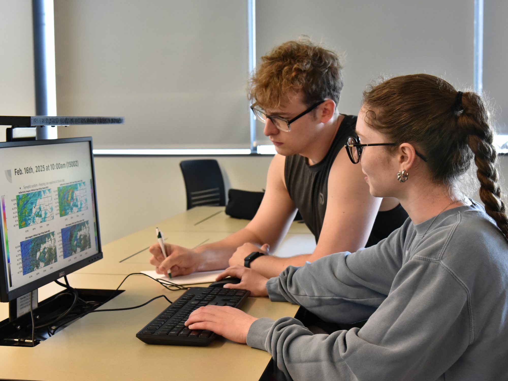 Tom White and Zoe Bush, who just earned their meteorology degrees in May, look over data from their research with Climavision related to gap-filling radar