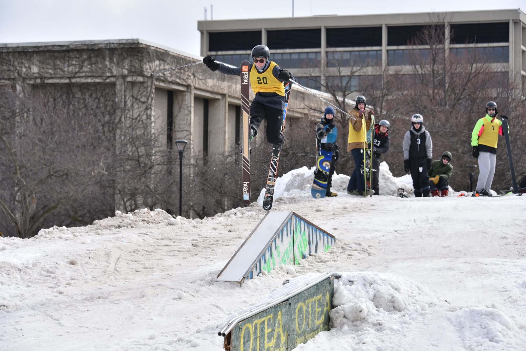 Skiers and snowboarders smile while standing atop a giant snow mound at a past Rail Jam