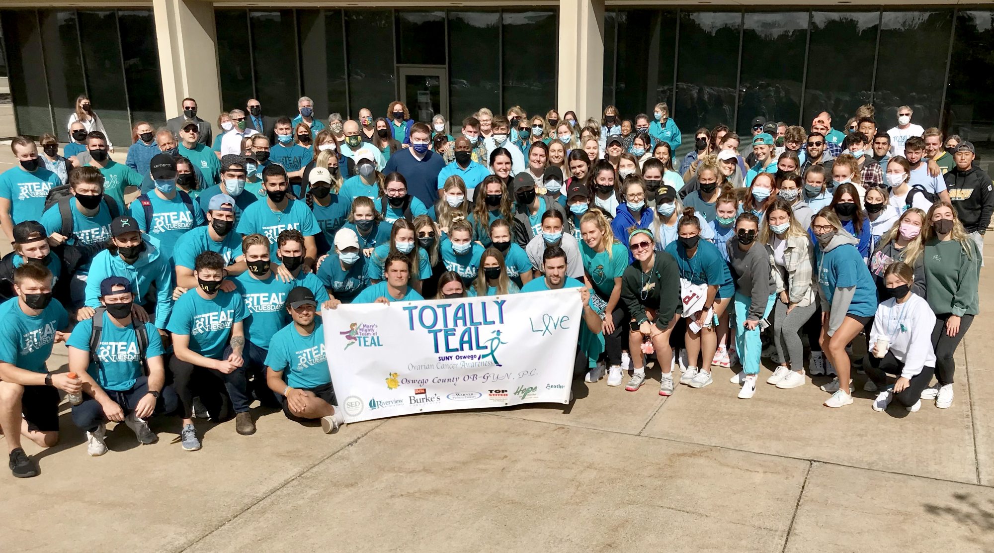 SUNY Oswego campus community members in a group wearing teal