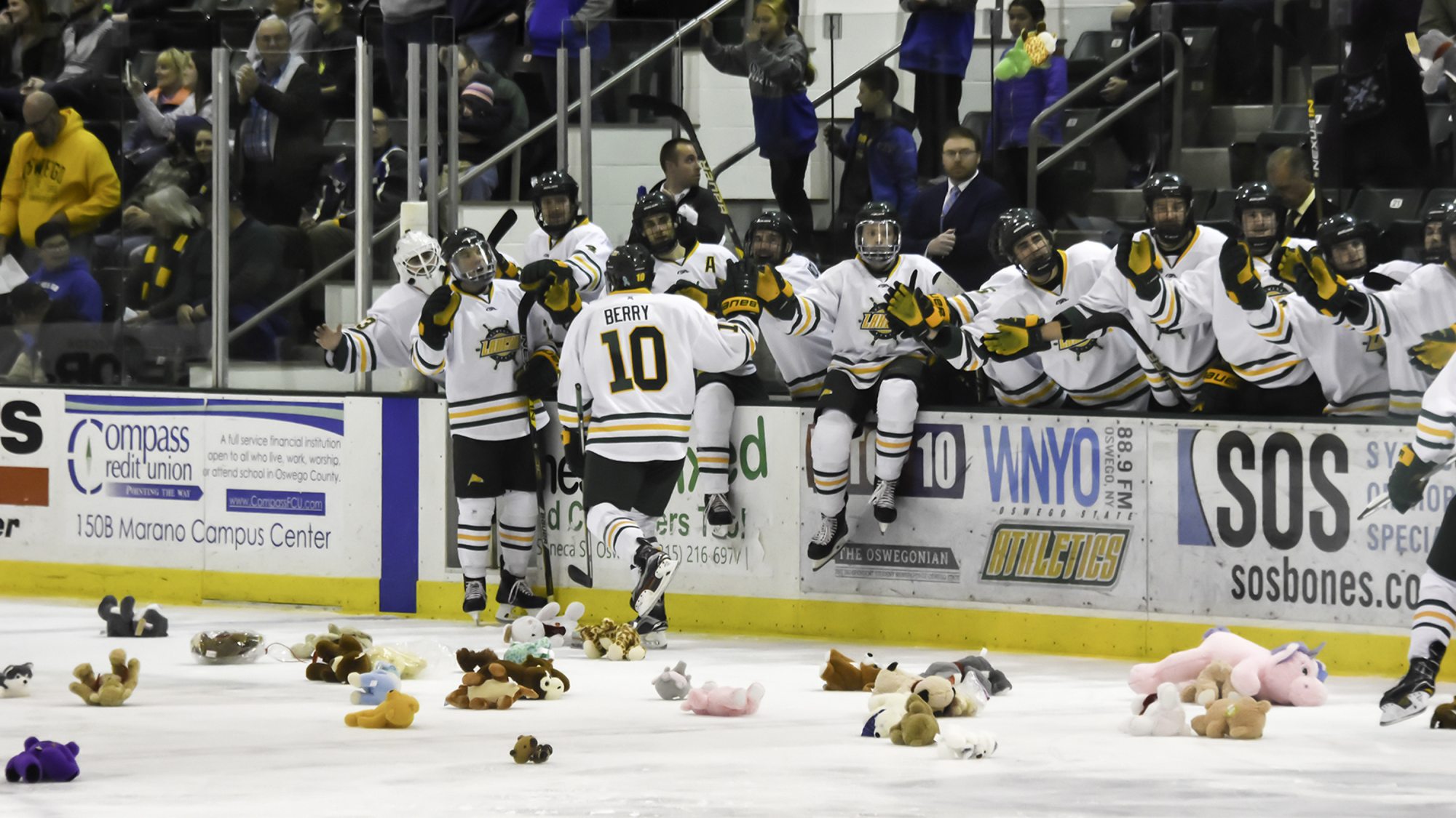Laker hockey players celebrate goals on fans toss stuffed bears on the ice in support of Toys for Tots