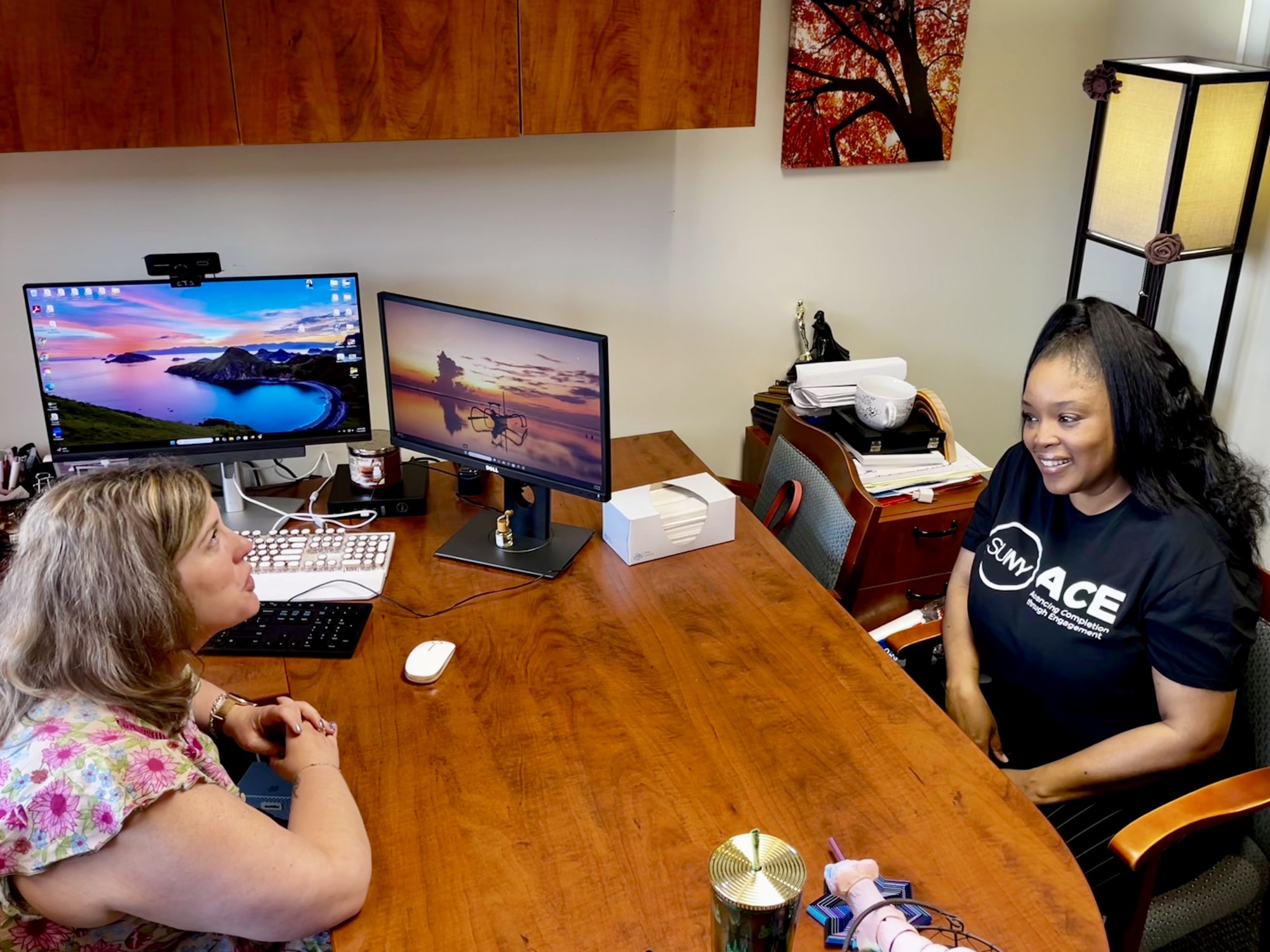 SUNY Oswego communications major and Advancing Completion through Engagement (ACE) student Melinda McCarthy (left) speaks with advisor Megan Runge in the Advisement Center.