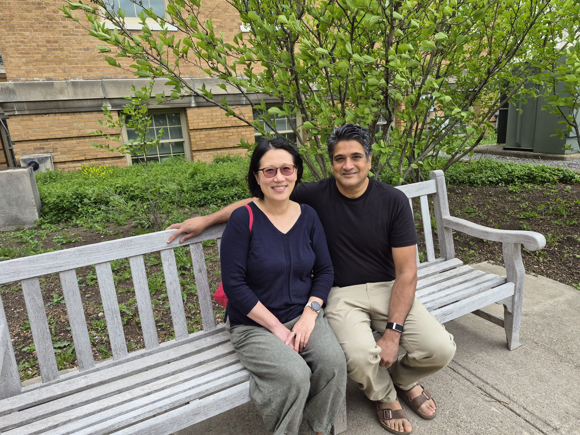 Julie Oh and Neelesh "Neel" Shah sit on a bench in front of Sheldon Hall