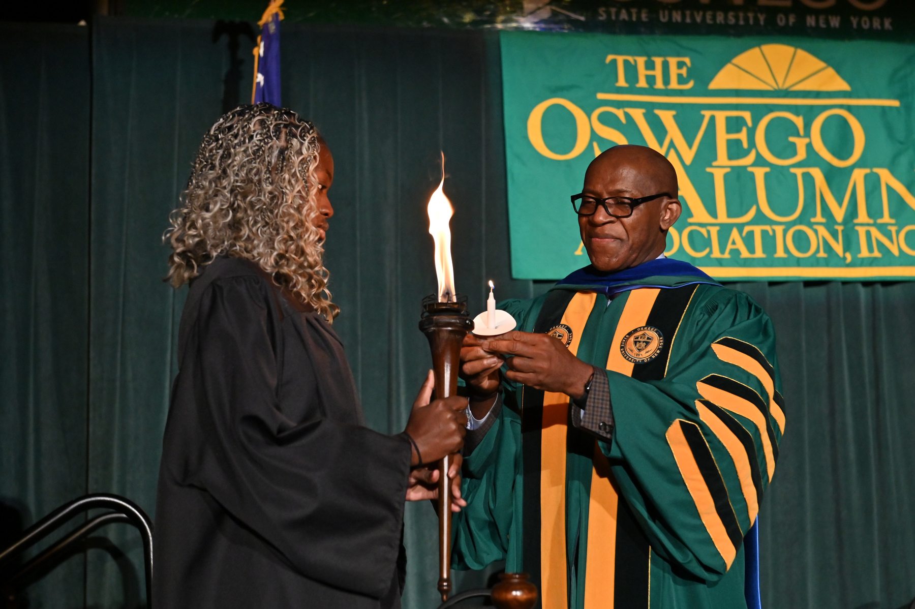 Student Association President Precious James lights the Torch of Learning with President Peter O. Nwosu during this year's Welcoming Torchlight Ceremony