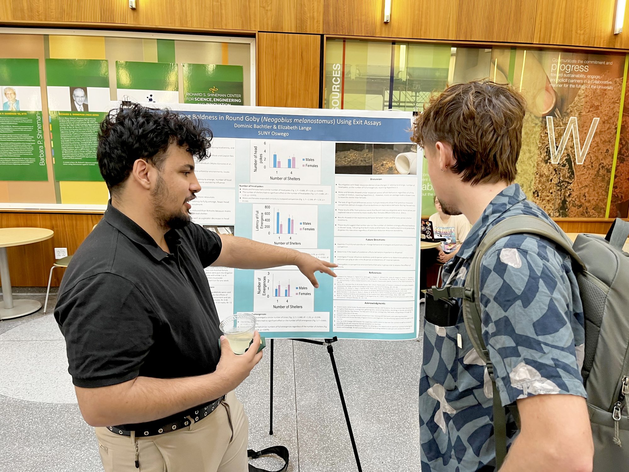 Dominic Bachtler explains the research poster, “Measuring Boldness in Round Gobi (Neogobius melanostomus) Using Exit Assays,”at the Fall 2026 Scholarly and Creative Activities Poster Symposium