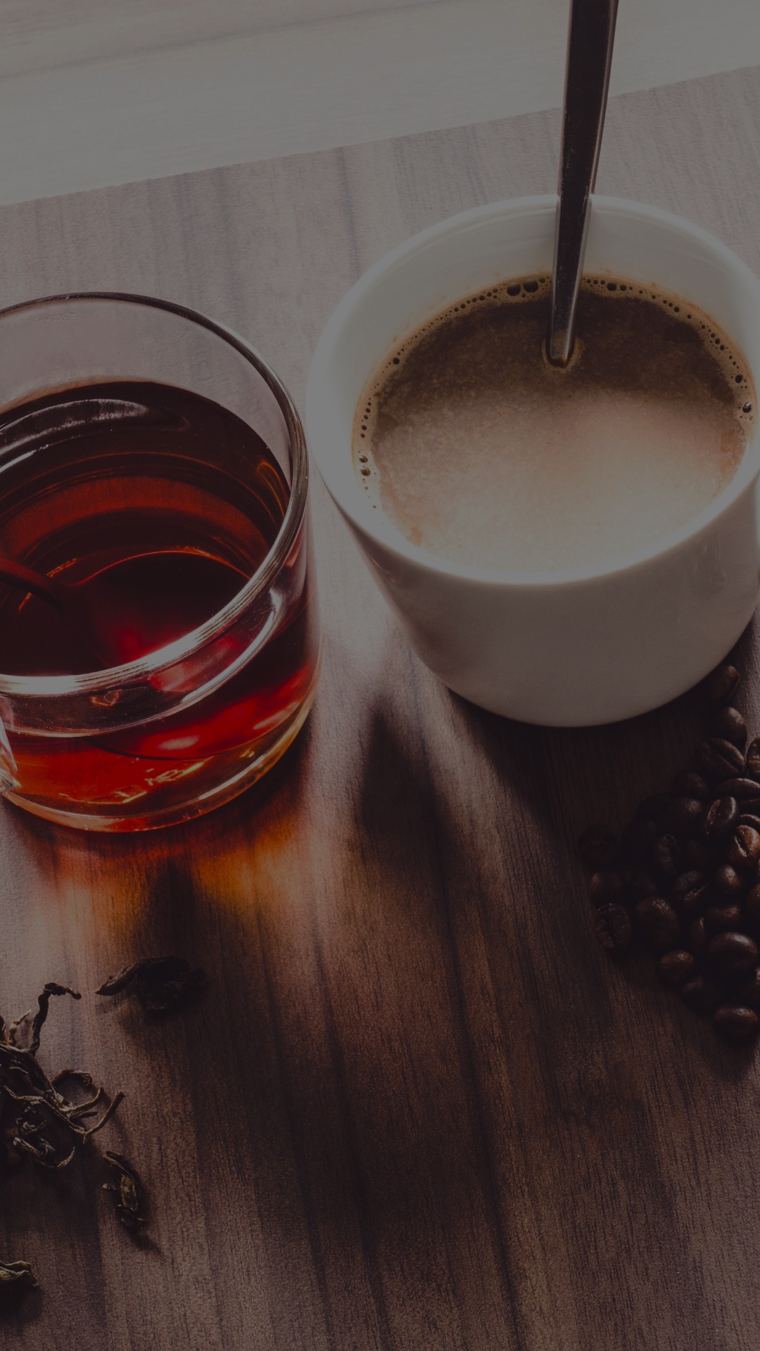 A cup of coffee and tea are on a table.