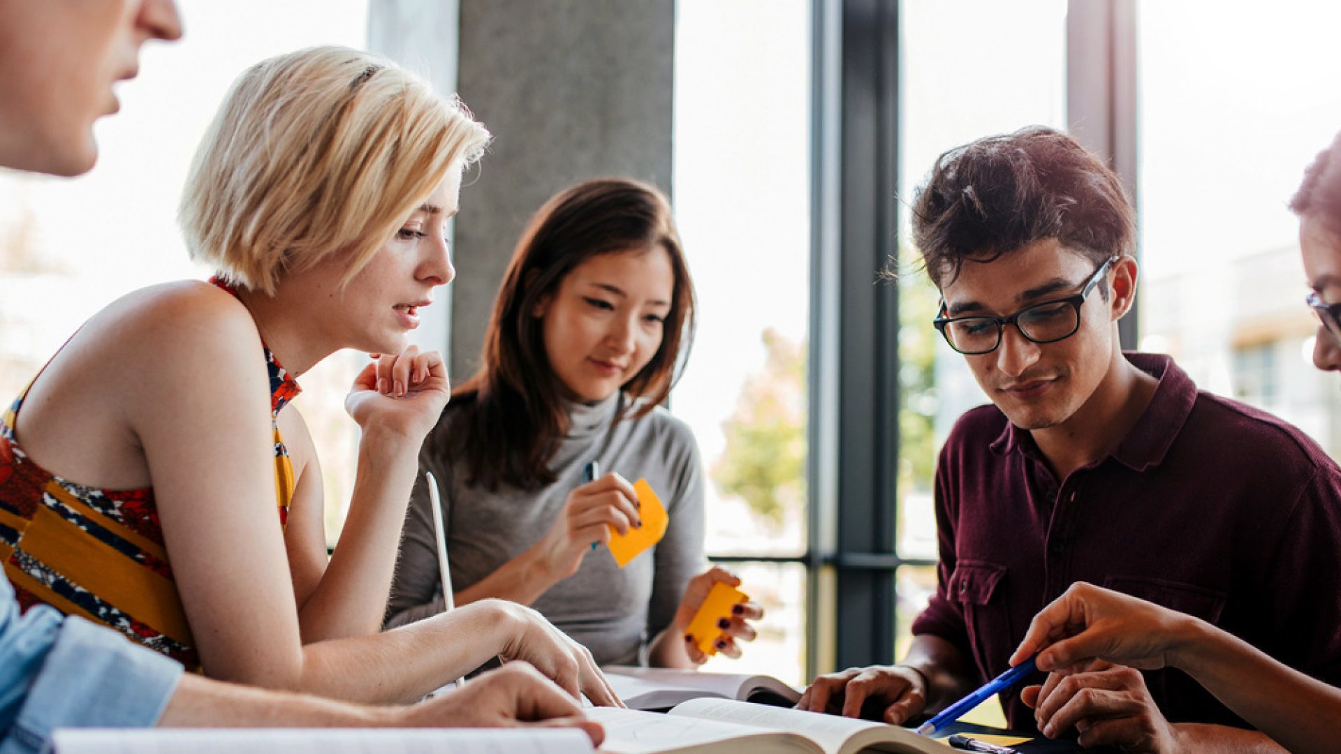 A group of college students work together to study a topic. 