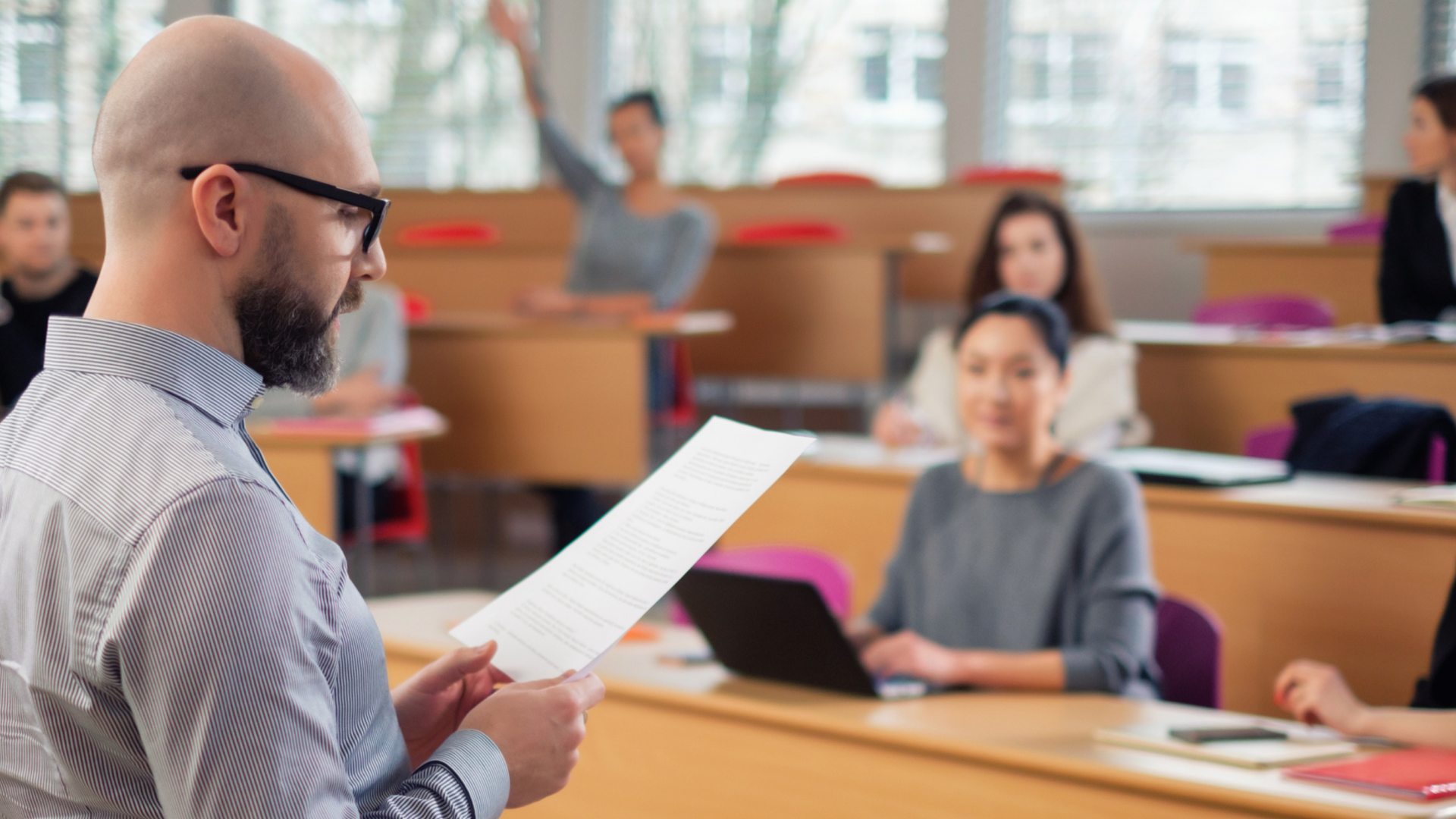 Professor reads from notes to a class of college students. 