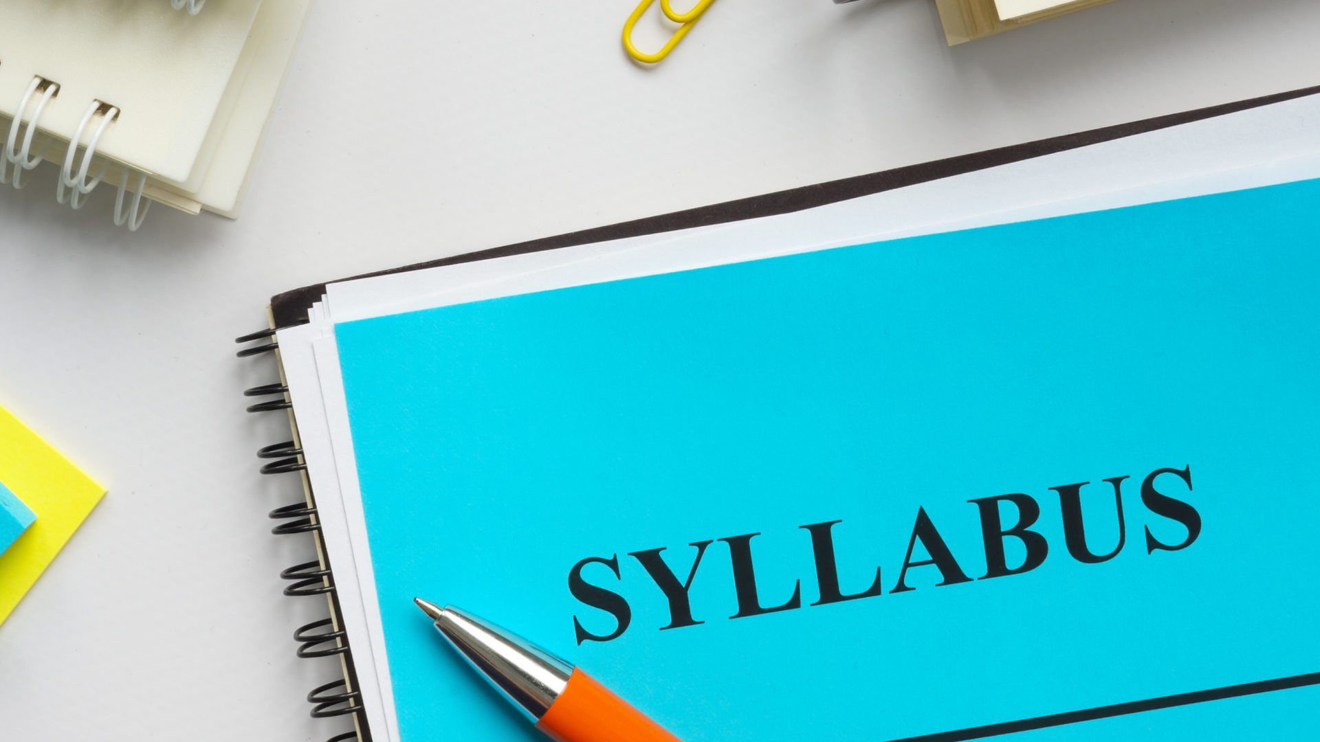 Notebook with syllabus laying on top of it. 