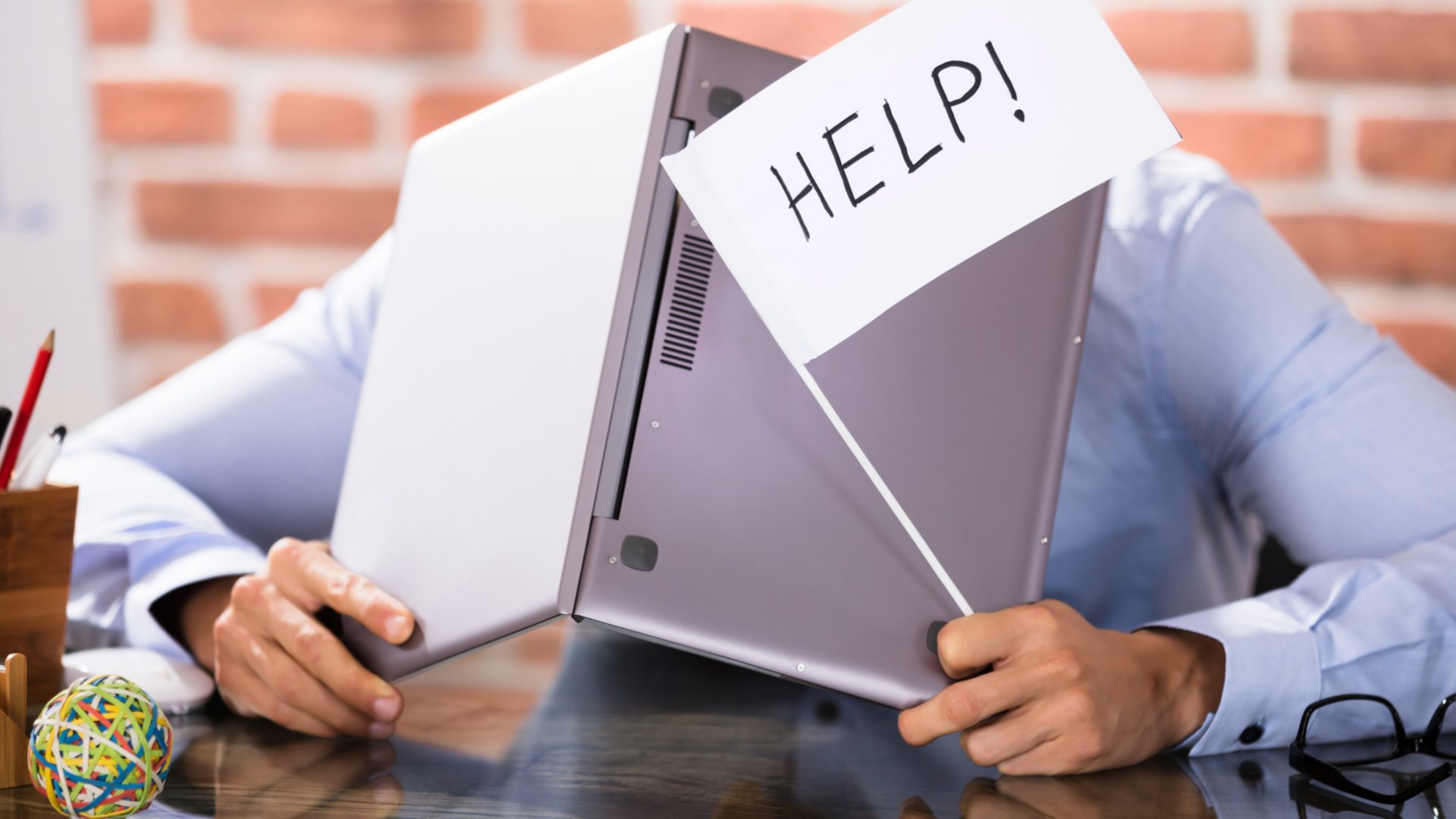 Young man with head inside of laptop. Holding up flag that reads "help!".