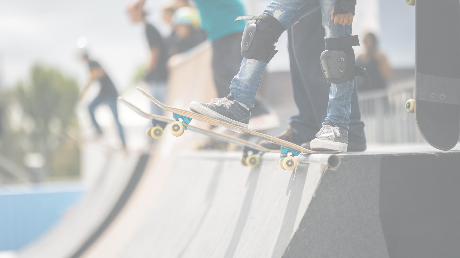 A line of skateboarders stand at the top of a half pipe waiting to drop-in.