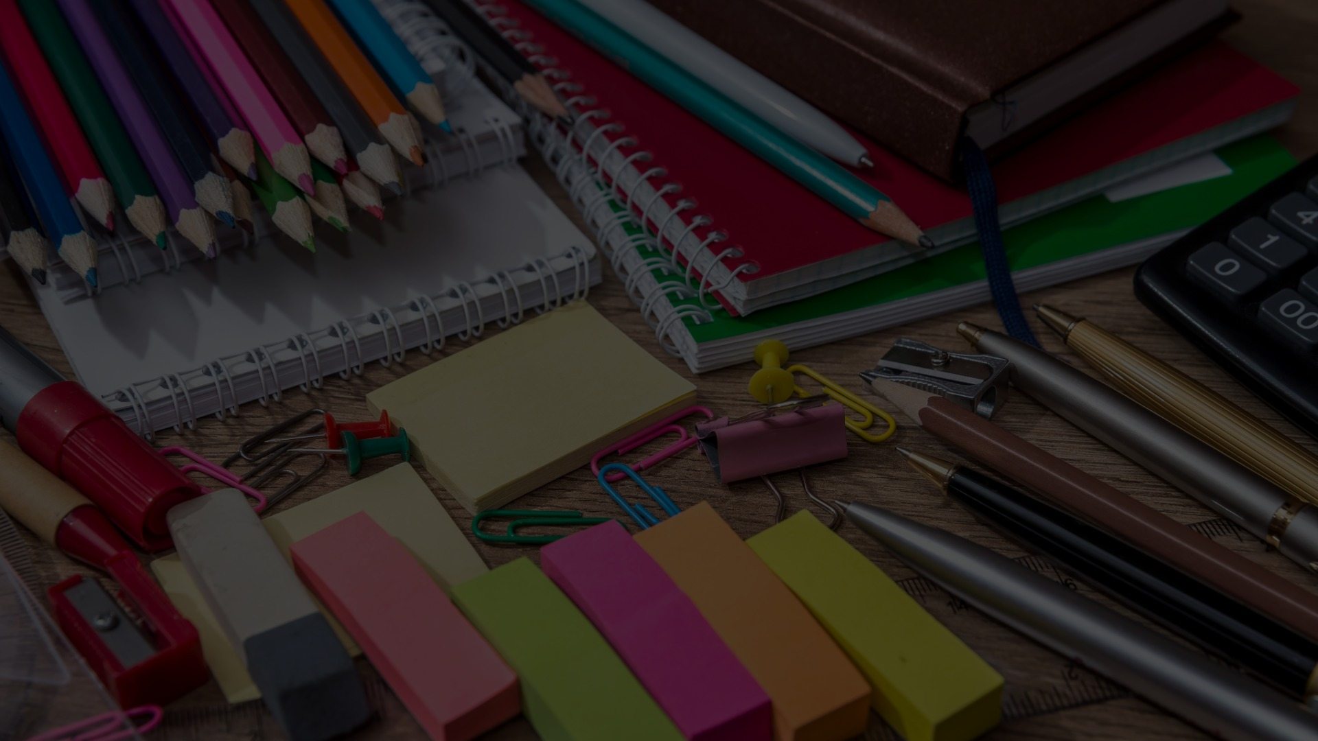 Brightly colored office supplies are strewn across a desk.