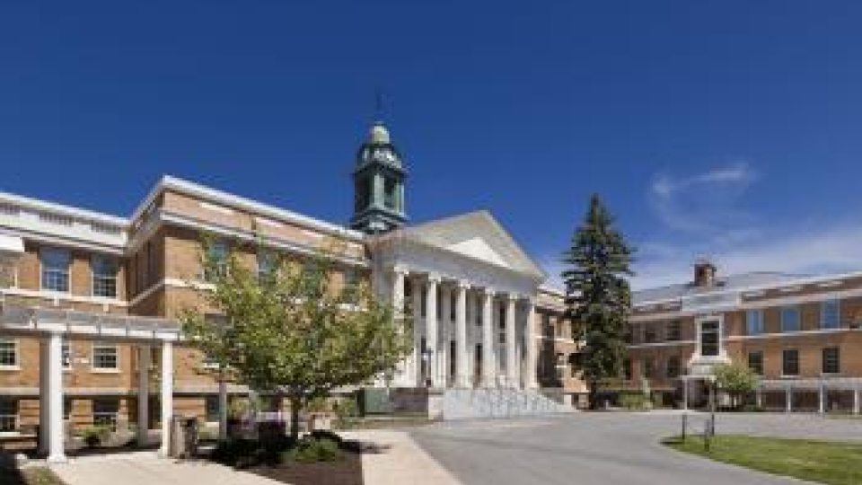 Front view of Sheldon Hall on a clear day, featuring its neoclassical architecture with a central clock tower and columns at the entrance.