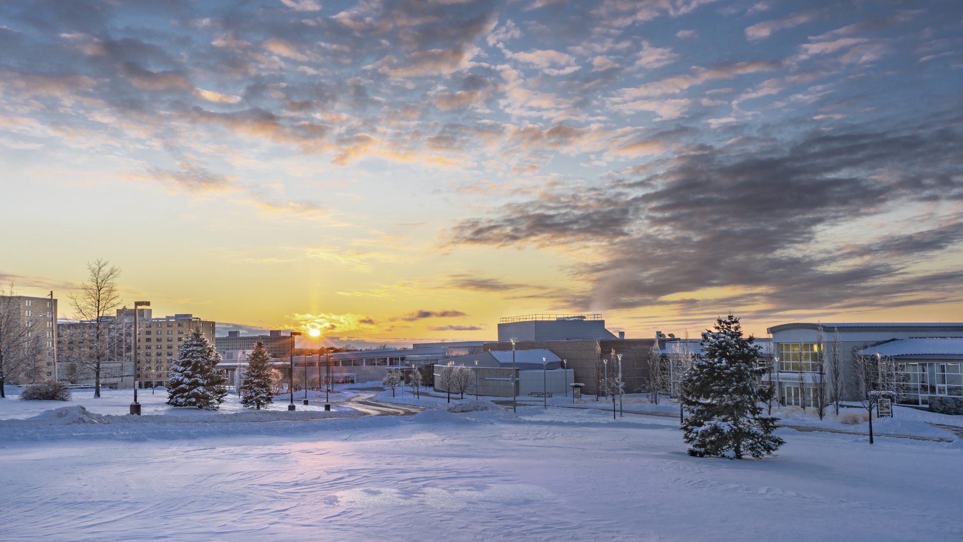 Campus in the winter with snow on the ground and the sun setting