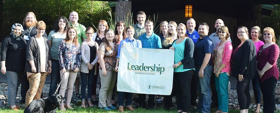 A group of people holding the Leadership Oswego County banner
