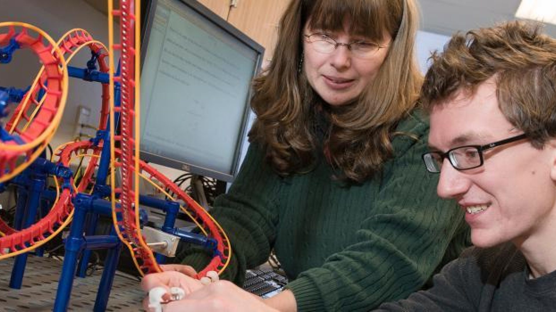 Professor guiding physics student through a roller coaster project