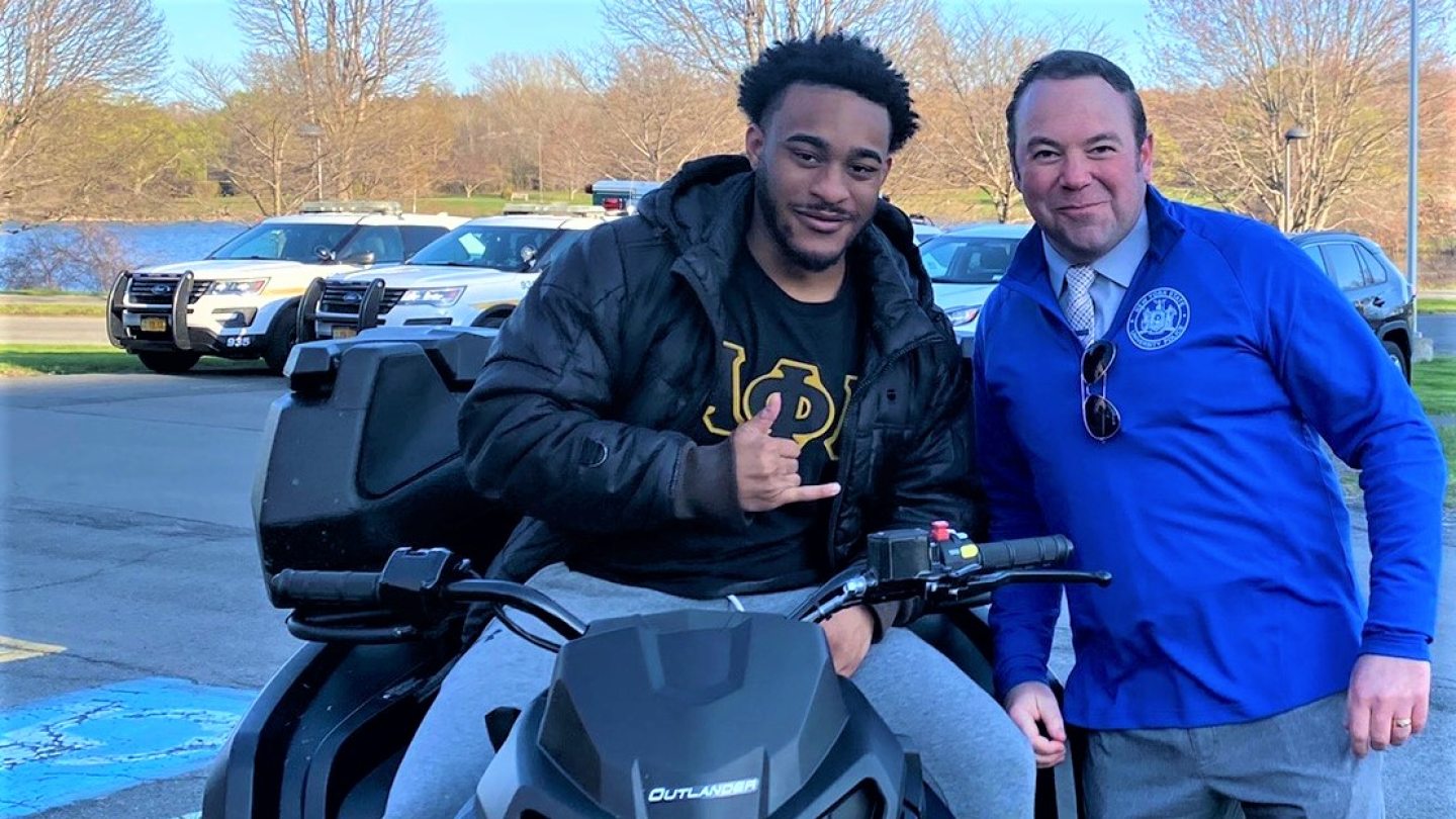 Chief Swayze posing with a student who is sitting on a 4-wheeler