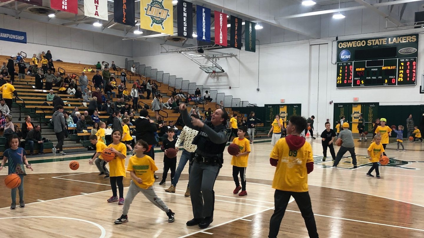 A University Police officer takes a shot at a basket during a youth basketball game