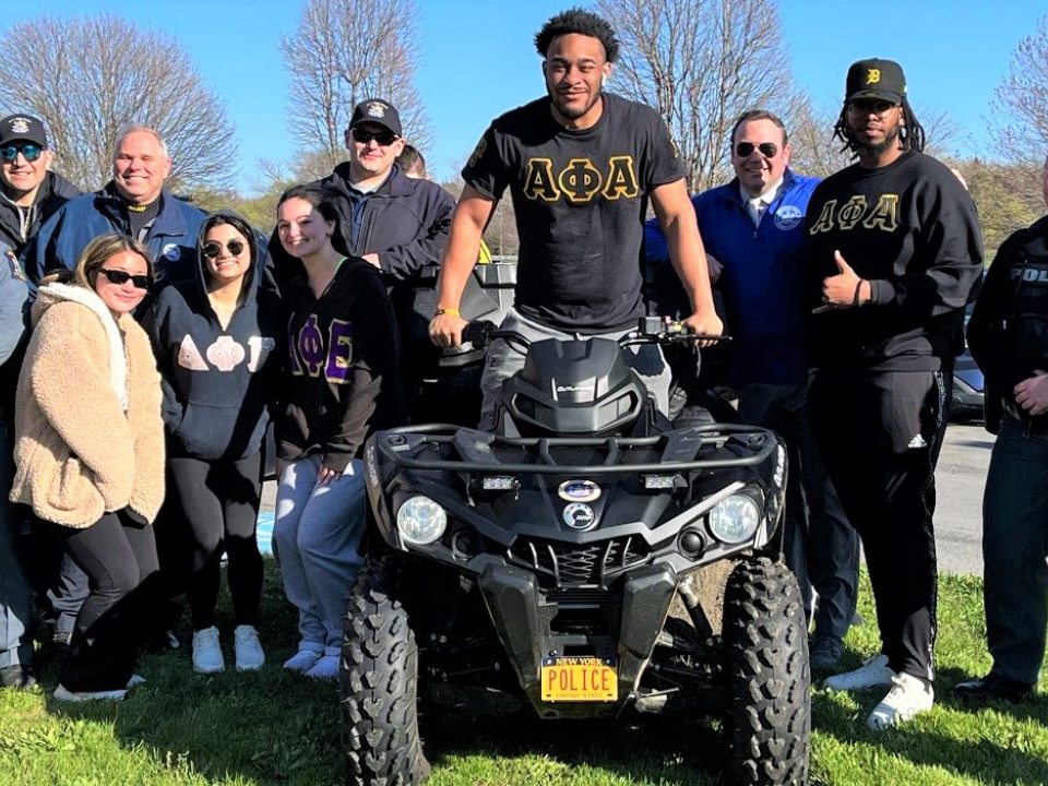 A group of students with University Police officers. One student is sitting on a 4-wheeler.