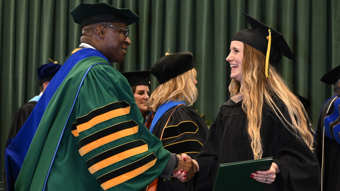 President Nwosu shakes hands with a graduate
