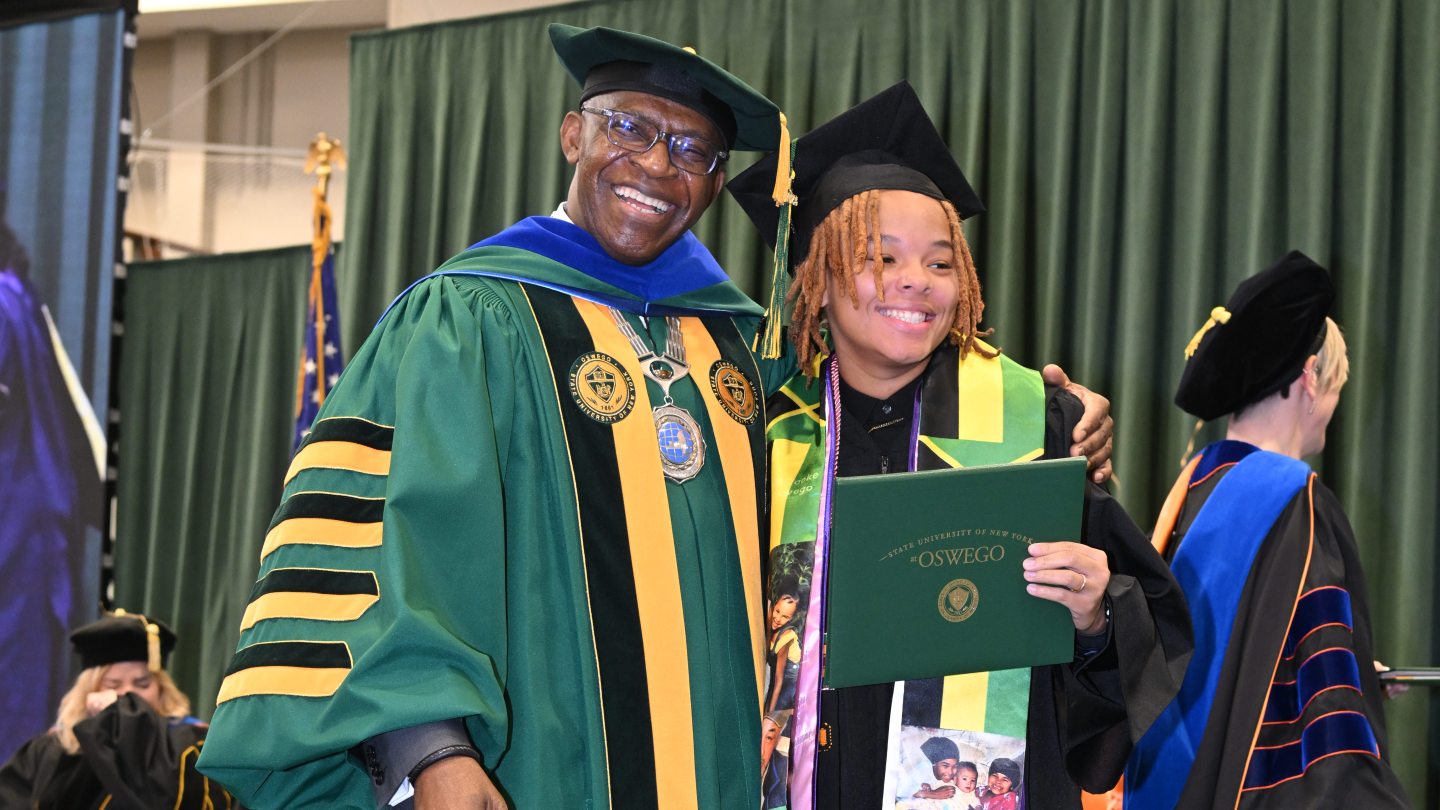President Nwosu poses for the camera with a graduate student who is holding their diploma
