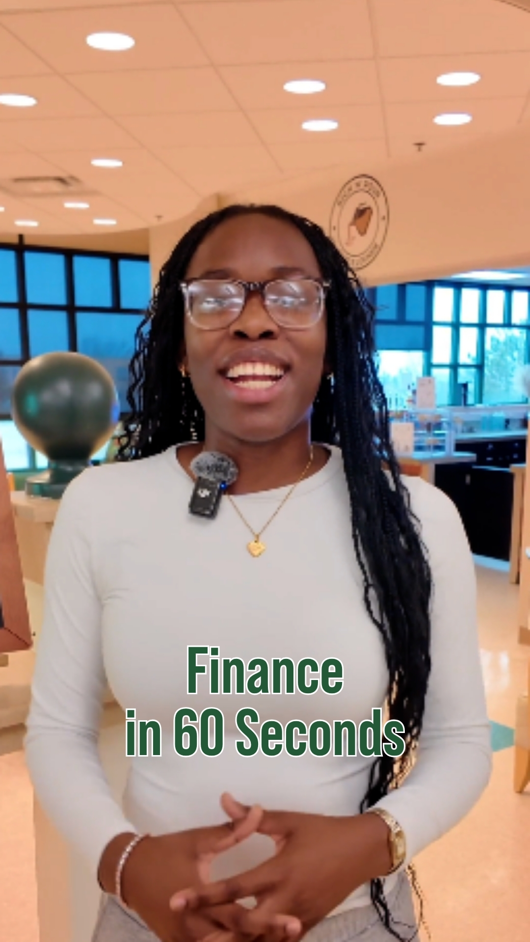 A student standing in front of the student run cafe, with on-screen text reading “Finance in 60 Seconds.”