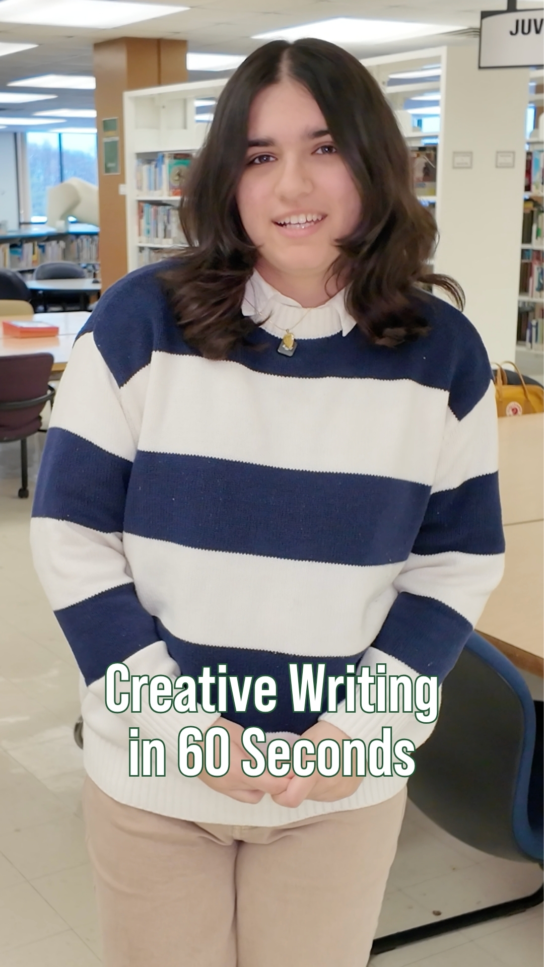 Student standing in a campus library wearing a blue-and-white striped sweater, smiling toward the camera. On-screen text reads “Creative Writing in 60 Seconds.”