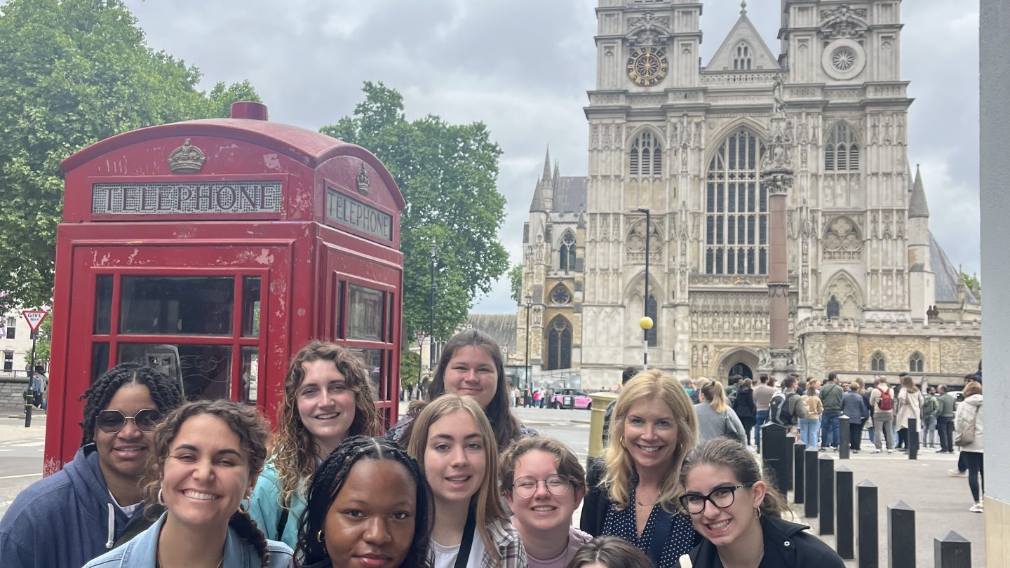 Students in a study abroad program, in front of a red telephone booth and a large cathedral