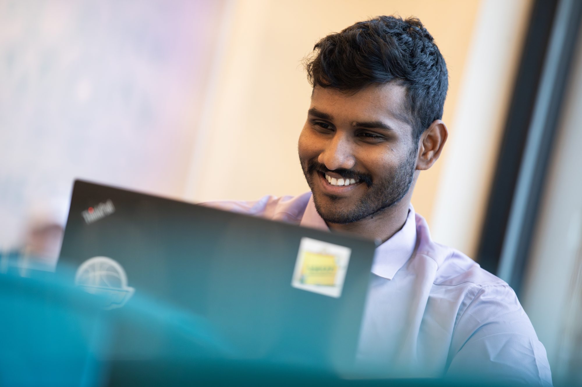 male student working on a laptop and smiling
