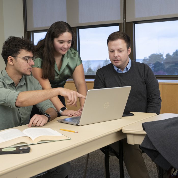 three graduate students working around a laptop
