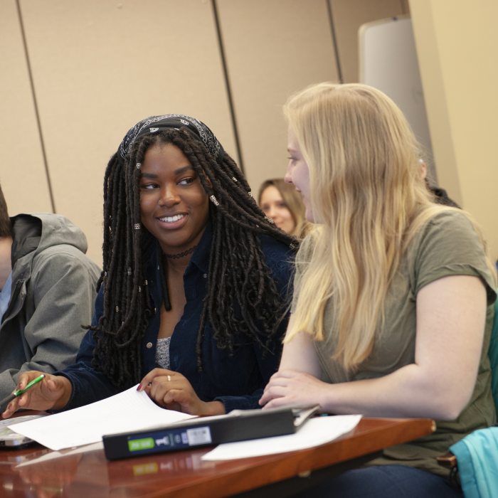 two female students talking in a classroom