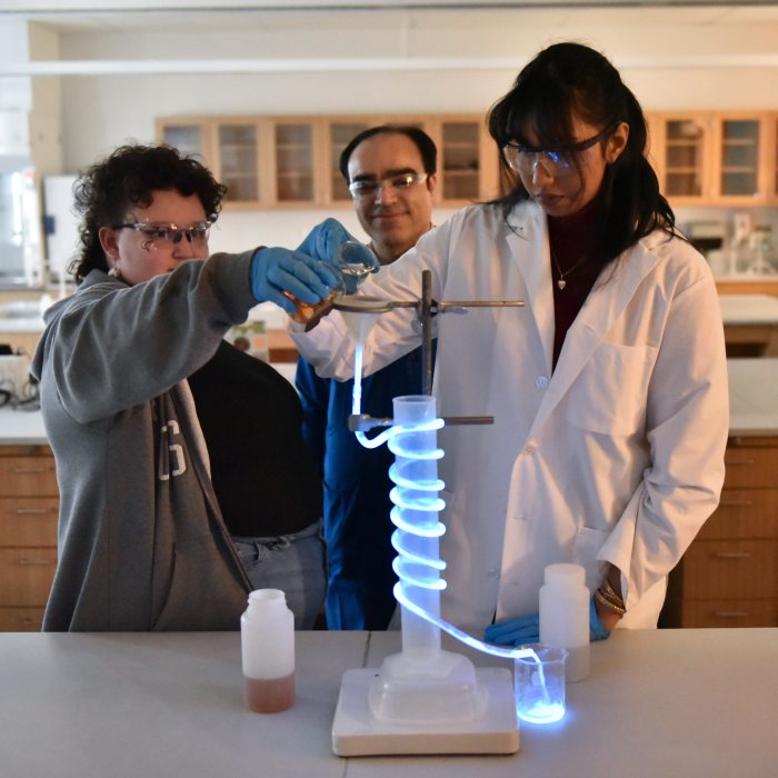 Students and a faculty member conduct a chemistry experiment in a laboratory.