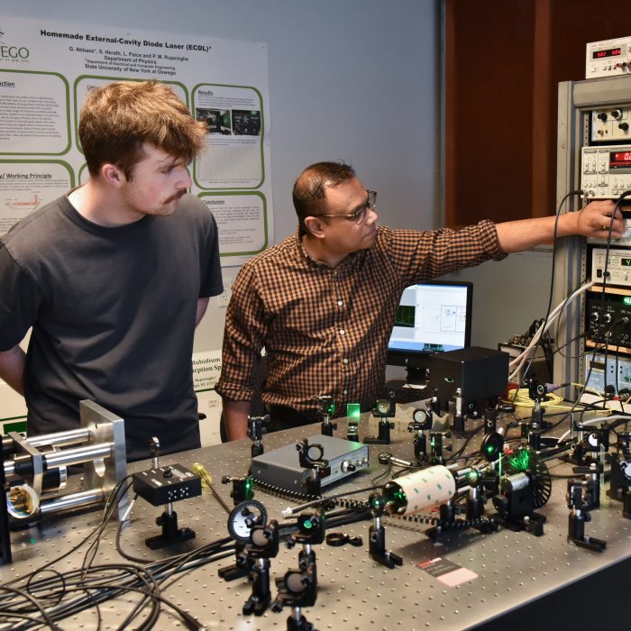 A physics student works with a faculty member in a research lab.