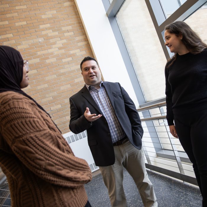 An educational leadership faculty member engages with students in conversation.