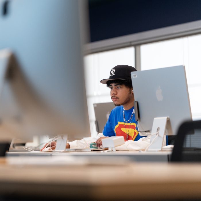 A graphic design student works at a desktop computer in a digital media lab.