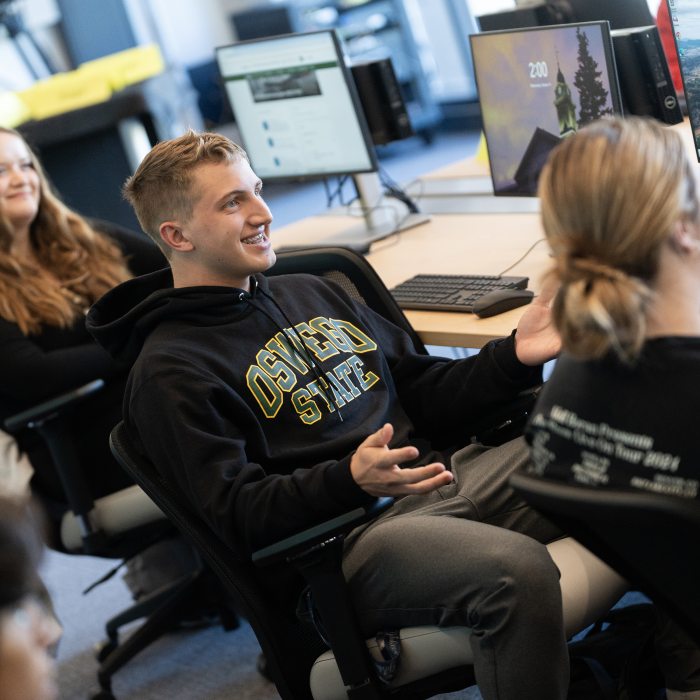Students seated at computer workstations in a classroom.