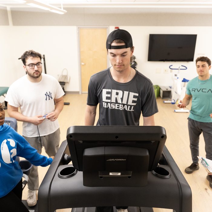 Students look on as their classmate is on a treadmill.