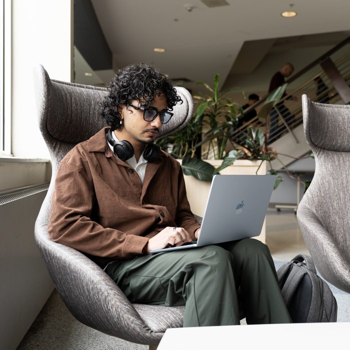 Student working on a laptop in a modern study lounge.