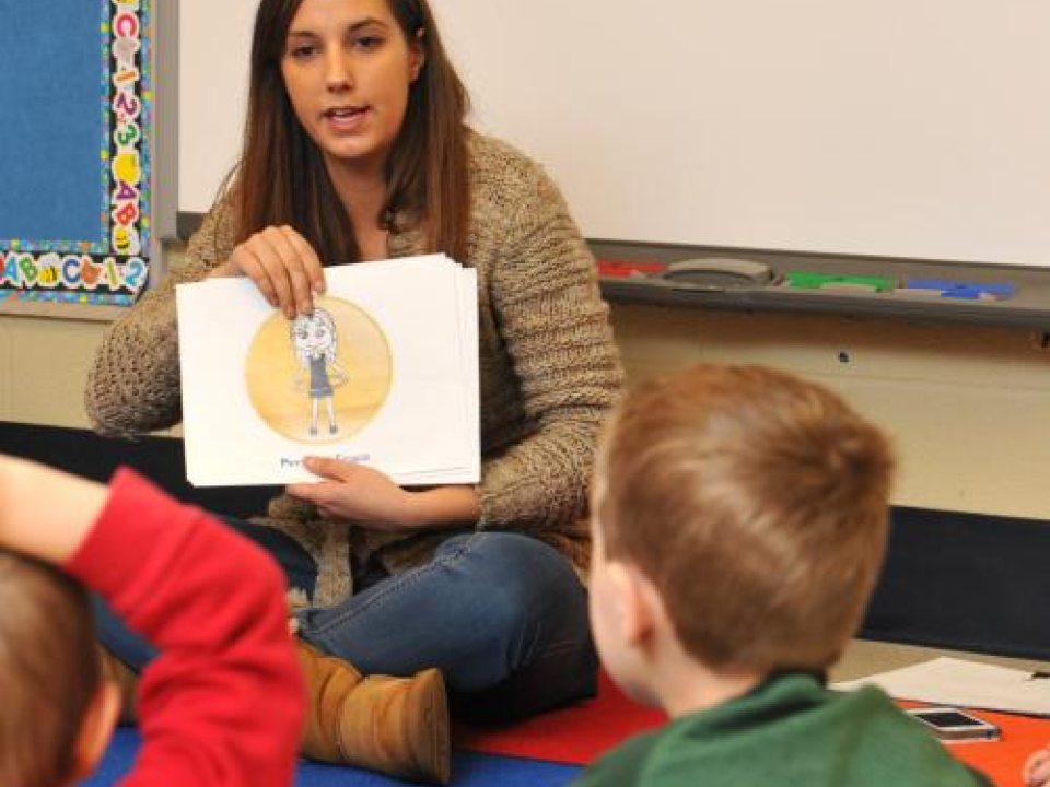 Student reading a book to children