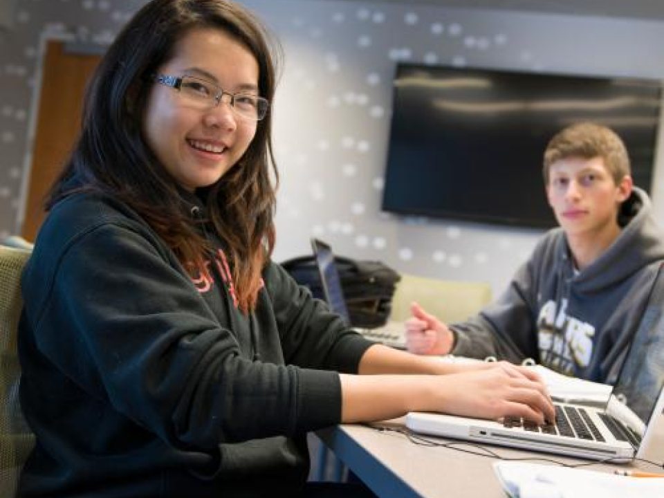 Students on laptops smiling at the camera