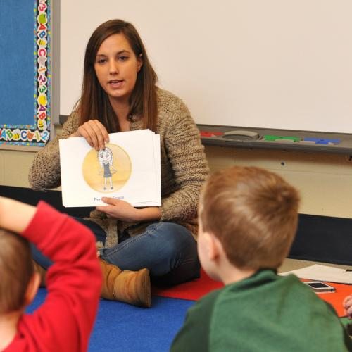 Student reading a book to children