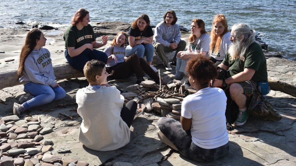 A group of students sitting in a circle at the edge of the lake