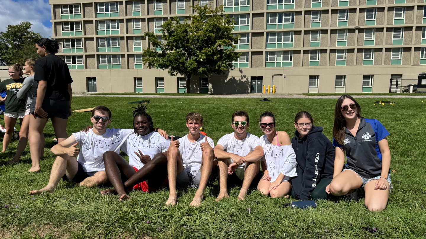 Seven students sitting on the grass. 