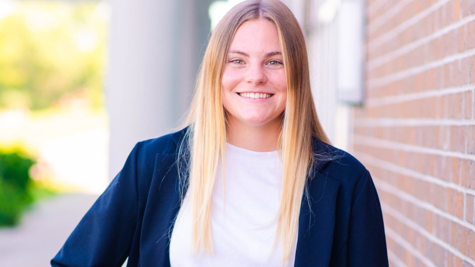 Head shot of Taylor next to a brick wall.